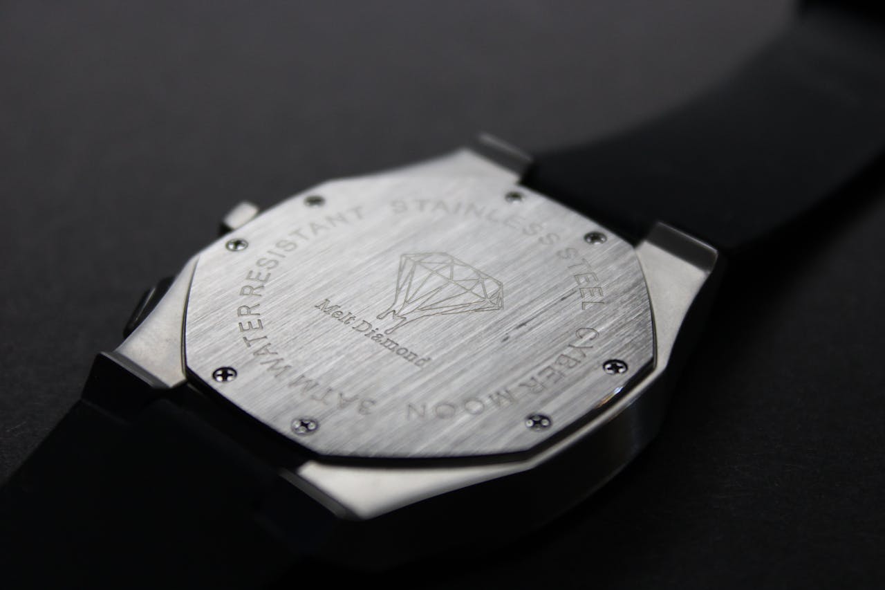 Close-up of a modern wristwatch with brushed stainless steel backplate featuring detailed engravings.