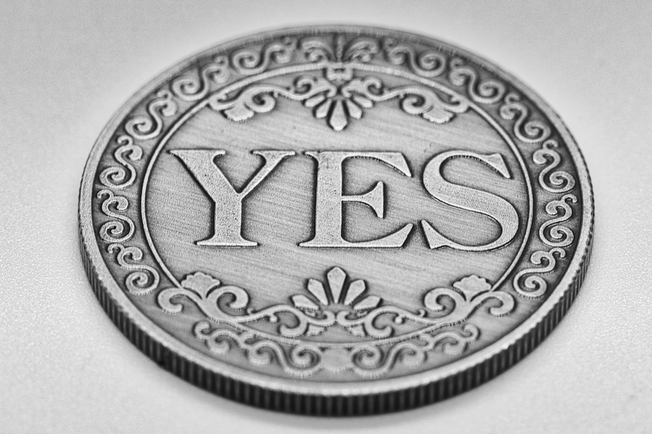 Close-up of a decorative coin with 'YES' inscribed, featuring intricate patterns and metallic shine.